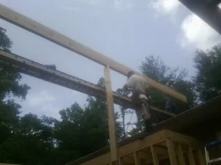Carpenter setting a ridge beam over a new addition frame — Ice Dam Removal by Roofing Brothers in Evart