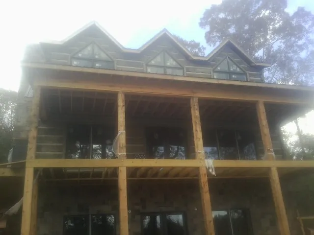 Dormers and porch framing on a large log home under construction — Roof Coating work by our crew in Evart