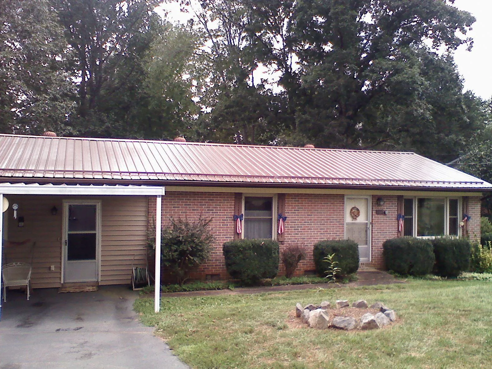 Bronze metal roof and carport on a brick ranch home — Roof Repair work by our crew in Evart
